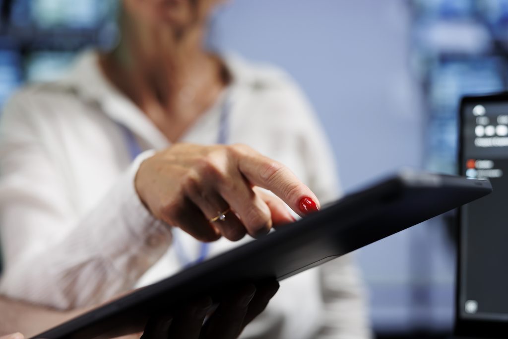 Relógio de ponto digital em destaque com colaborador registrando a jornada de trabalho.